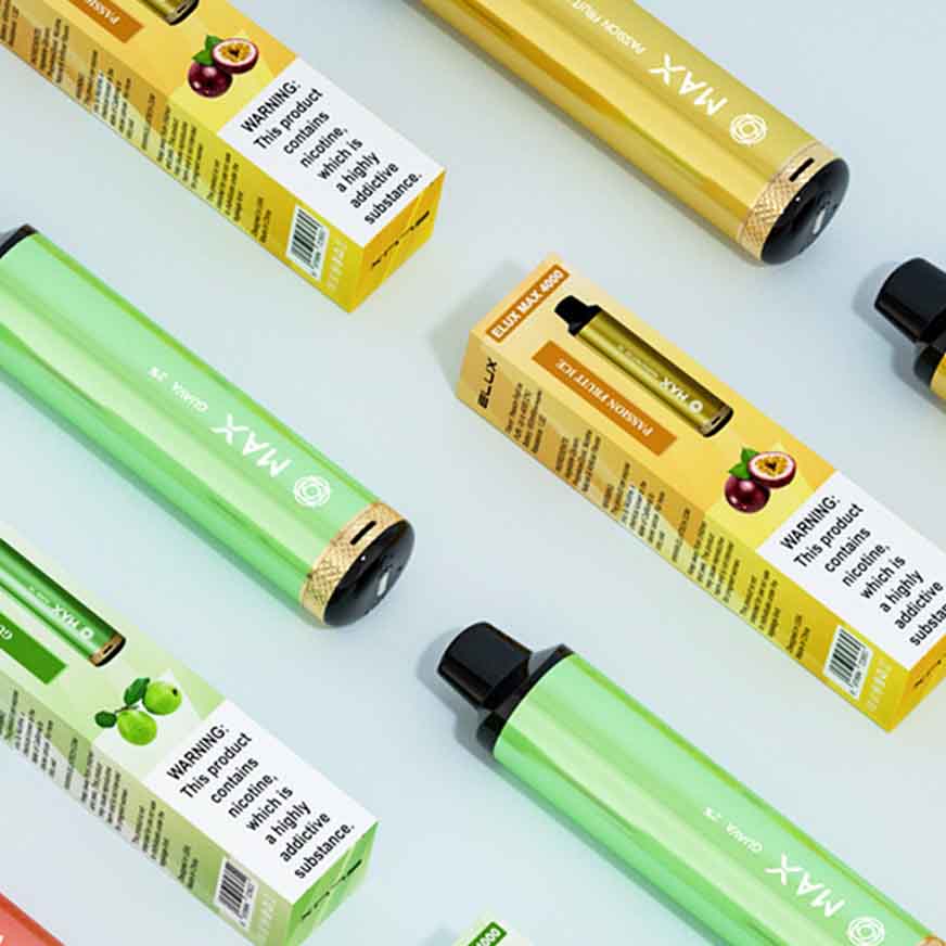 Assorted colorful vape pens with packaging displayed on a light surface, featuring different flavors like apple and passionfruit.