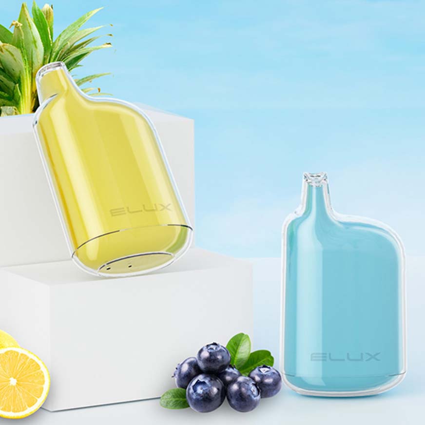 Two Elux e-liquid bottles, yellow and blue, placed on a white pedestal with fresh blueberries and a lemon slice nearby.