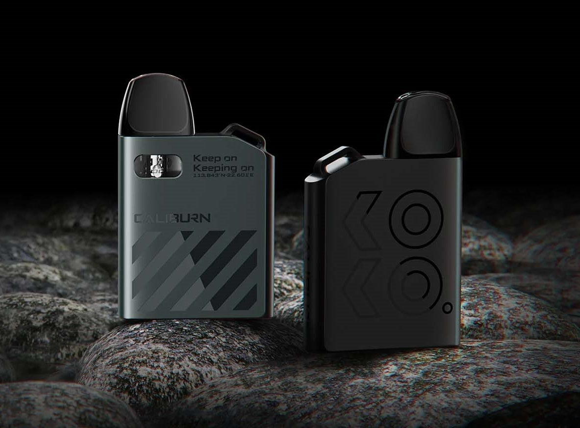 Close-up of two sleek vape devices on rocks with modern designs, showcasing a metallic and matte finish.