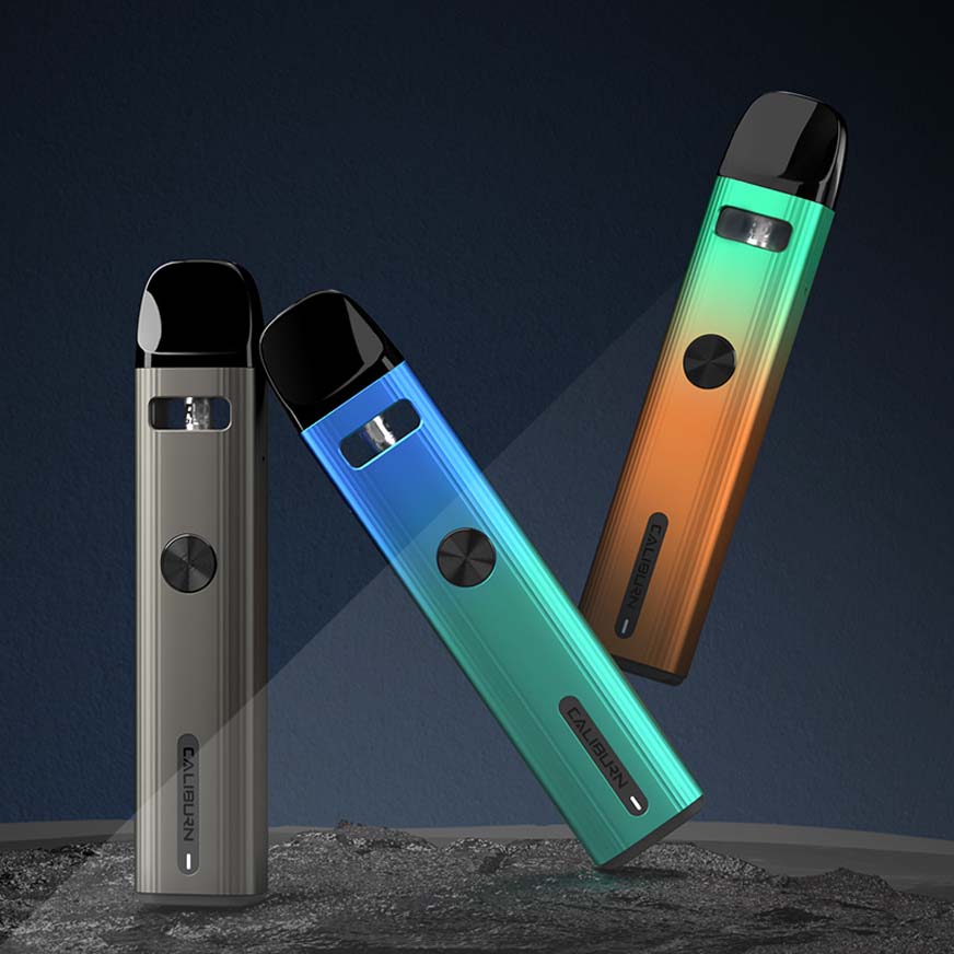 Three colorful vape pens standing upright on a textured surface against a dark background.