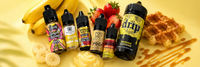 Five 10ml nic salt bottles and one 100ml shortfill bottle of banana vape juice arranged with fresh bananas, strawberries and waffle pieces on a pale yellow studio background.